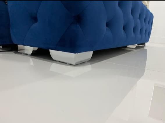 Blue tufted sofa placed on white tiled floor with shiny chrome legs.