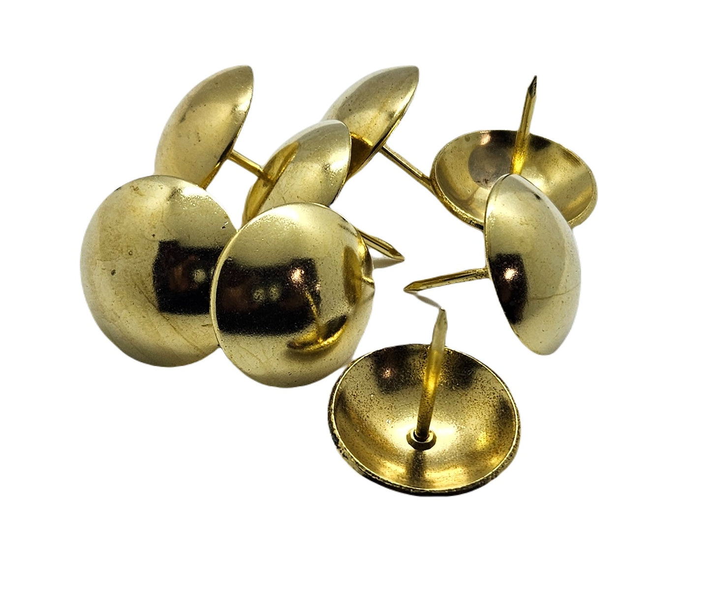 Shiny brass upholstery nails with round domed heads arranged on a white background.