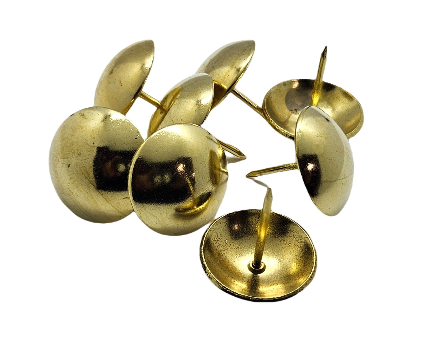 Shiny brass upholstery nails with round domed heads arranged on a white background.